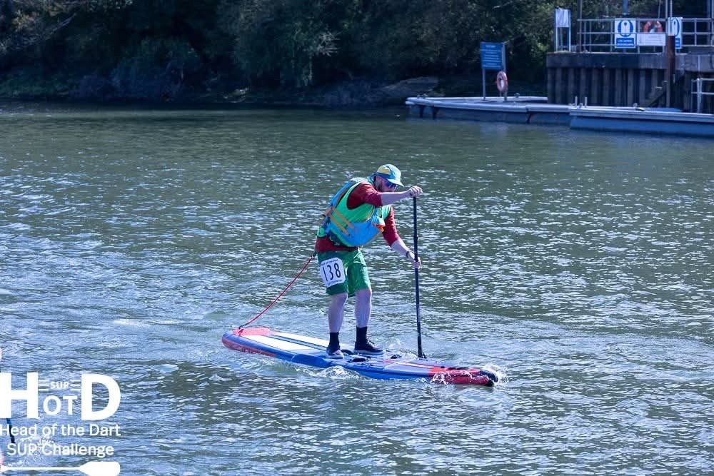 Person paddleboarding on a river during a SUP challenge event.
