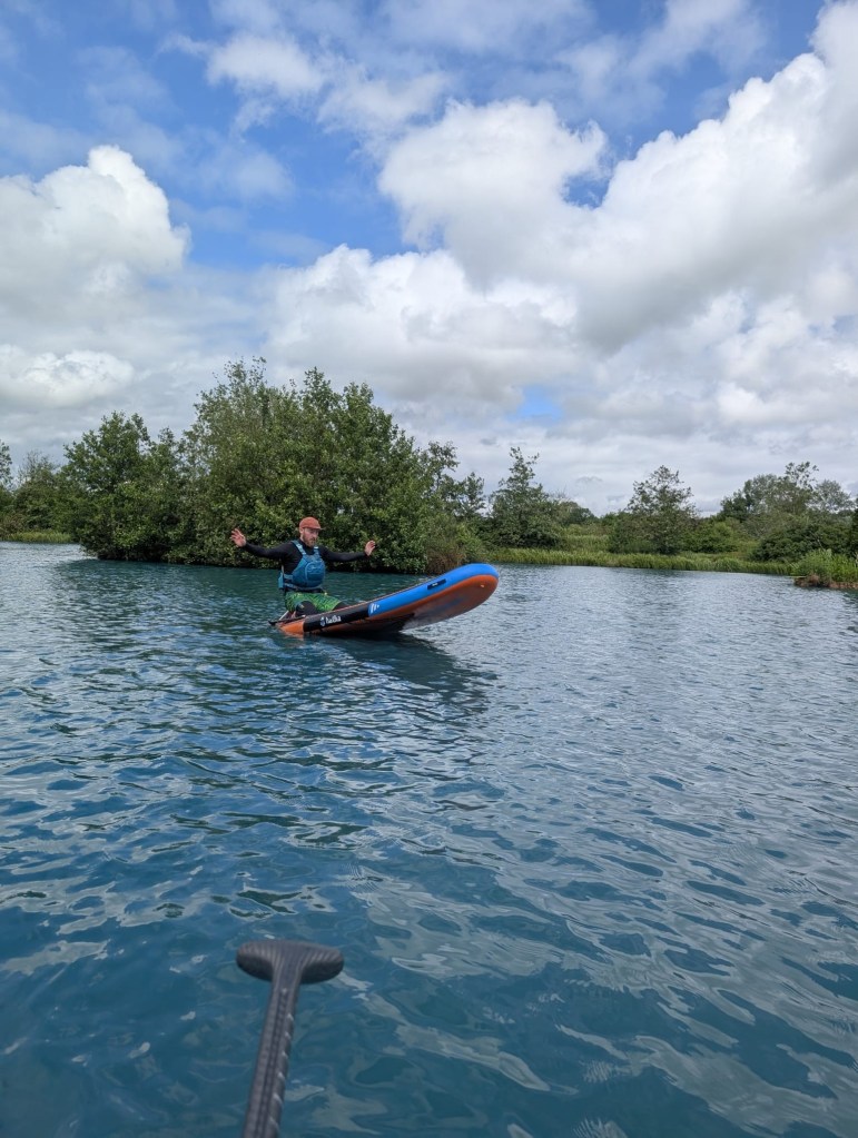 Person on paddleboard balancing on calm water under cloudy sky.
