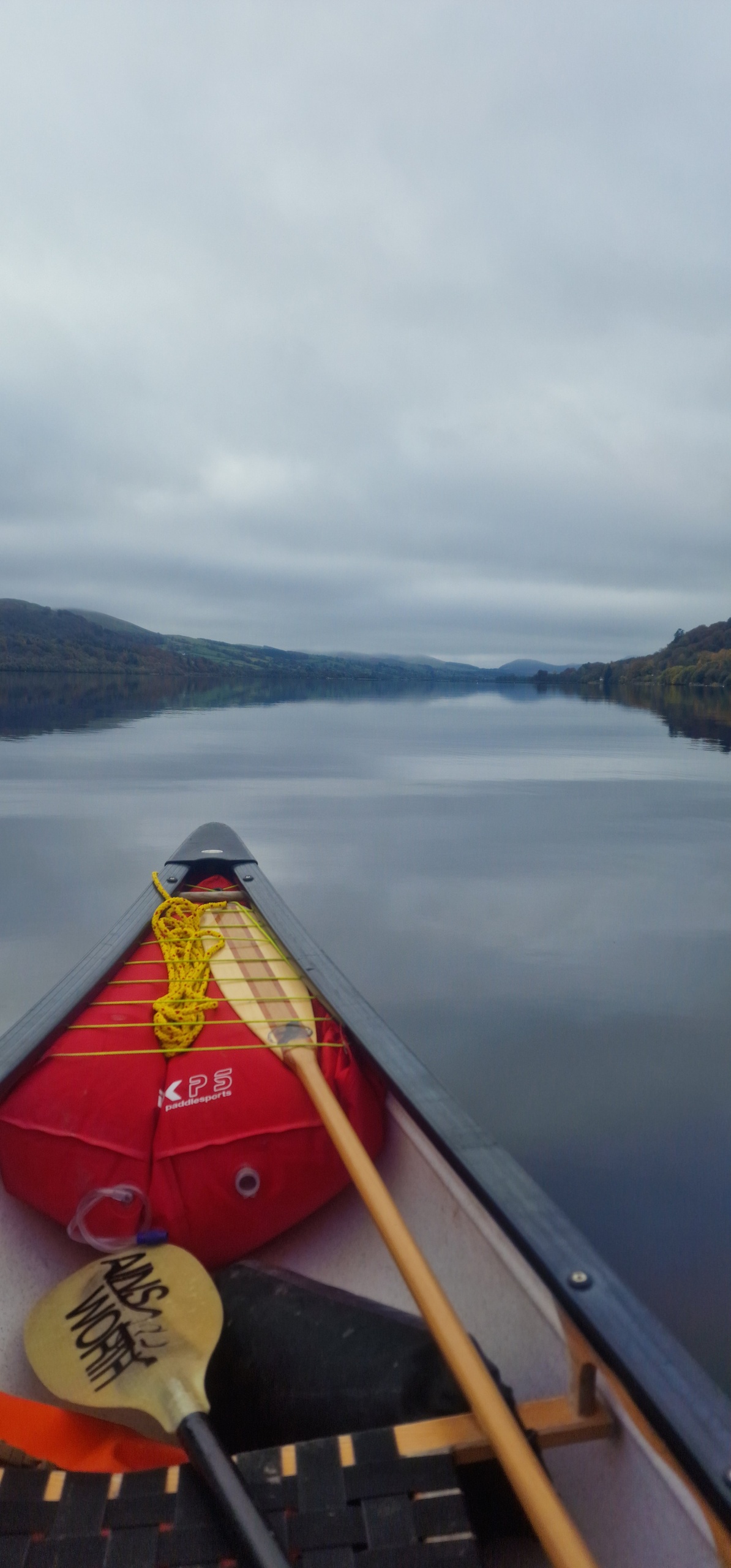 Canoe on calm lake with paddles and cloudy sky